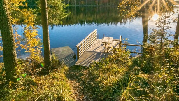 A wooden dock extending into a calm lake surrounded by trees. - Suvituuli by Interhome (Punkaharju)