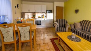 A compact living space with a dining area, kitchen, and seating area. - Tjalkstrasse by Interhome (Norddeich)