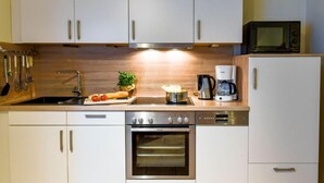A modern kitchen with white cabinets, stainless steel appliances, a microwave, and a coffee maker. - Tjalkstrasse by Interhome (Norddeich)