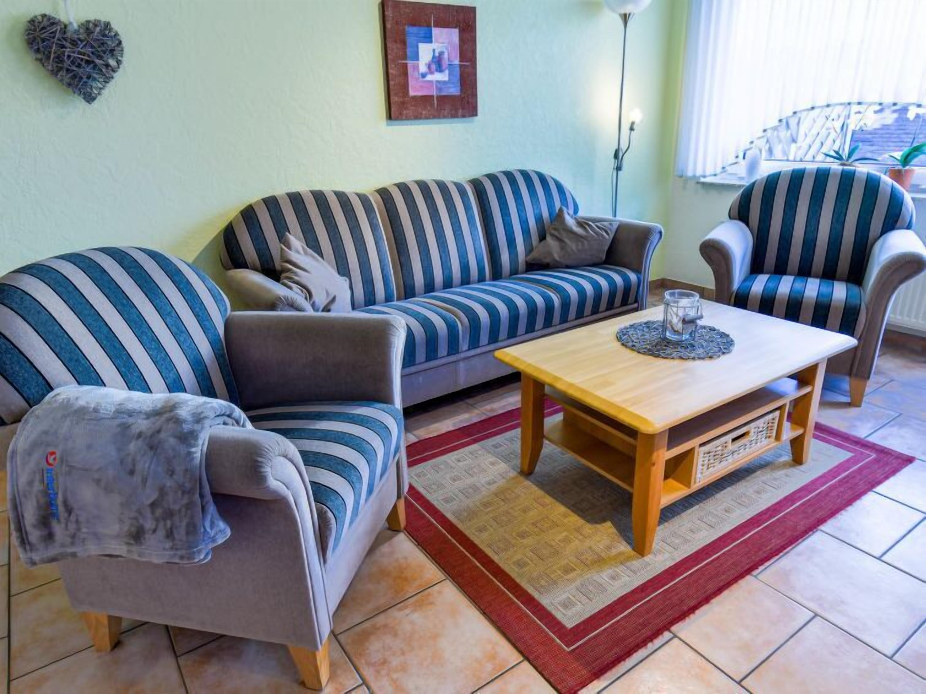 Ein Wohnzimmer mit einem gestreiften Sofa, einem Holztisch und gestreiften Sessel.