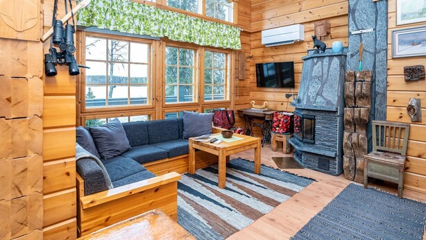 A cozy cabin interior with a wooden interior, large windows, a fireplace, and a television. - Rukaniemen kontio by Interhome (Kuusamo)