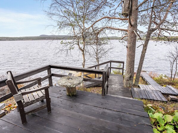 Eine Holzterrasse, die zu einem See führt, mit einer Bank und einem Vogelhäuschen.