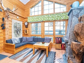 A cozy cabin interior with a wooden sofa, a coffee table, and a fireplace. - Rukaniemen kontio by Interhome (Kuusamo)