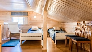Una camera da letto mansardata accogliente con due letti, una sedia, un tavolo e un tappeto decorato.