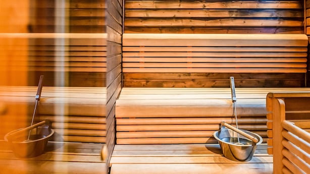 Una sauna con panche in legno e un catino di metallo a terra.