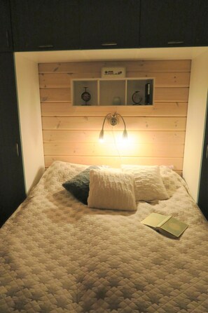 Ein Bett mit einer gesteppten Decke, zwei Kissen und einer Nachttischlampe.