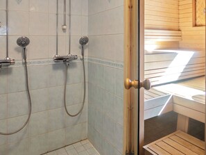 A shower with two handheld showerheads and a wall-mounted faucet.
