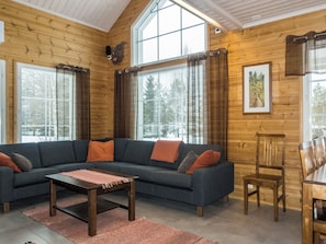A cozy living room with a sectional sofa, a coffee table, and a dining table with chairs. - Pyrykieppi by Interhome (Rovaniemi)