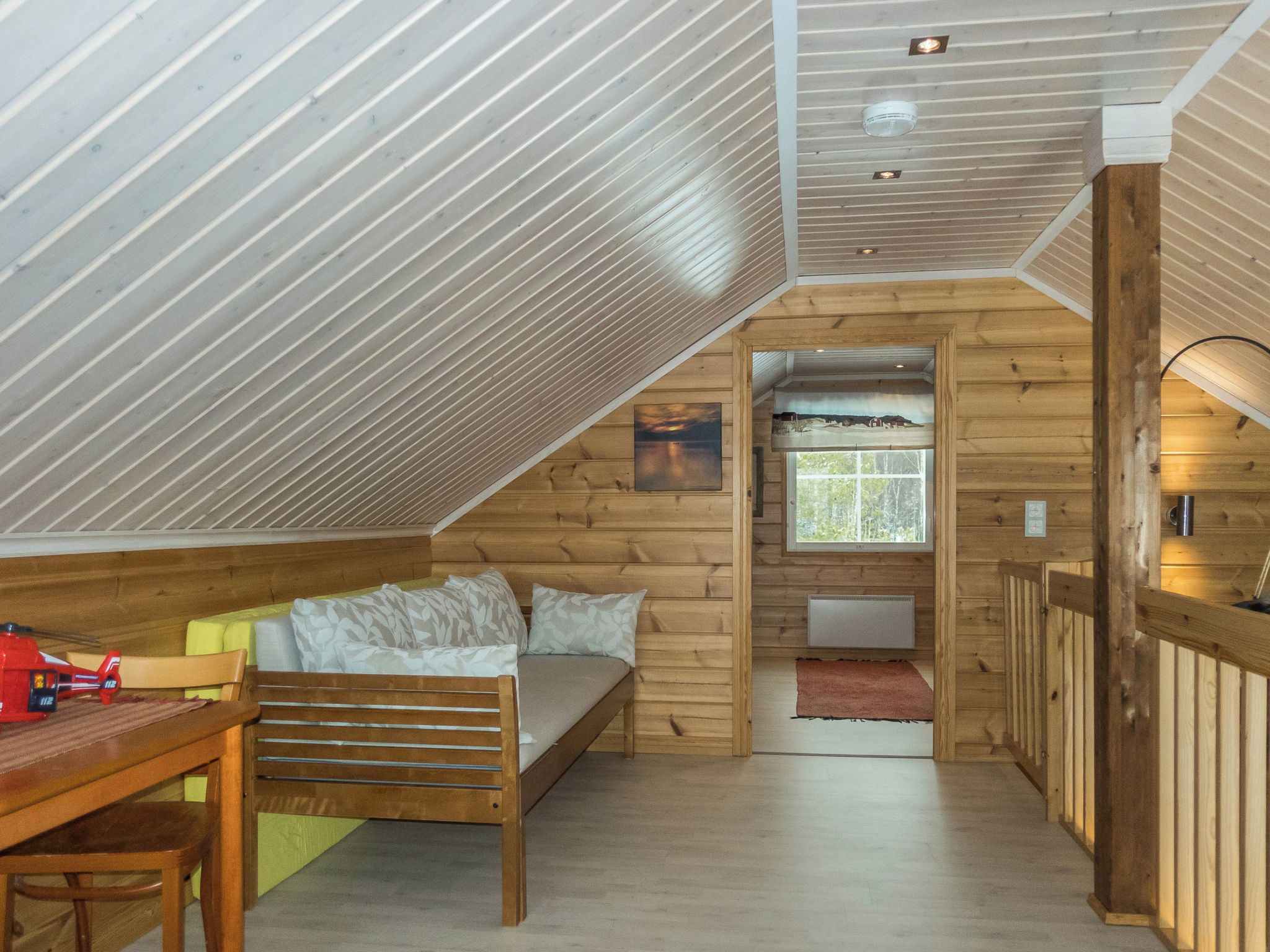A cozy cabin interior with a loft bedroom, a dining area, and a kitchen.