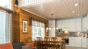 A cozy living room with a sofa, a dining table with chairs, and a kitchen area with cabinets and appliances. - Pyrykieppi by Interhome (Rovaniemi)