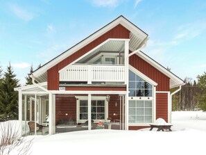 Kaksikerroksinen talo, jossa on parveke, suuret ikkunat ja katettu kuisti.