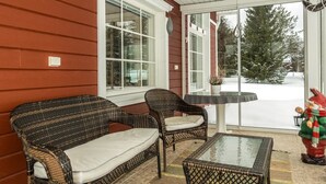 A covered porch with wicker furniture, a glass table, and a view of a snowy landscape. - Pyrykieppi by Interhome (Rovaniemi)