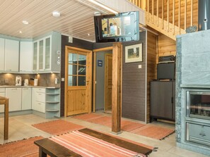 A modern kitchen with wooden cabinets, a built-in stove, and a television mounted on a wooden beam. - Pyrykieppi by Interhome (Rovaniemi)