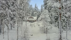 Eine verschneite Landschaft mit einem Gebäude, umgeben von Bäumen.