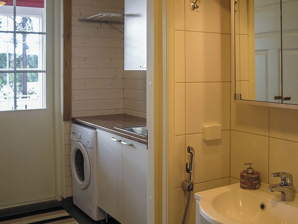 A compact kitchen with a washing machine, a sink, and a mirror. - Villa kukkula by Interhome (Multia)