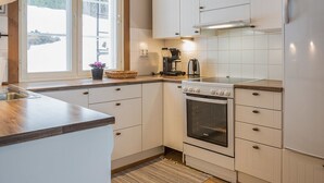Eine moderne Küche mit weißen Schränken, einem eingebauten Backofen und einer Kaffeemaschine auf der Arbeitsplatte.