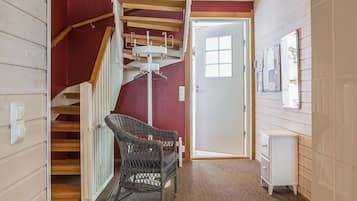 A staircase with wooden steps and a metal handrail, leading to a room with a white door and a wall-mounted bulletin board.