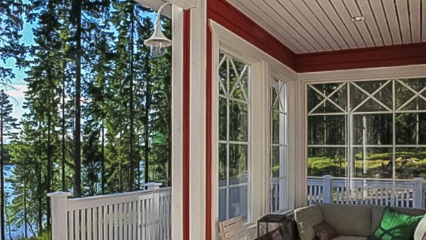 Eine überdachte Veranda mit Blick auf einen Wald und ein See.