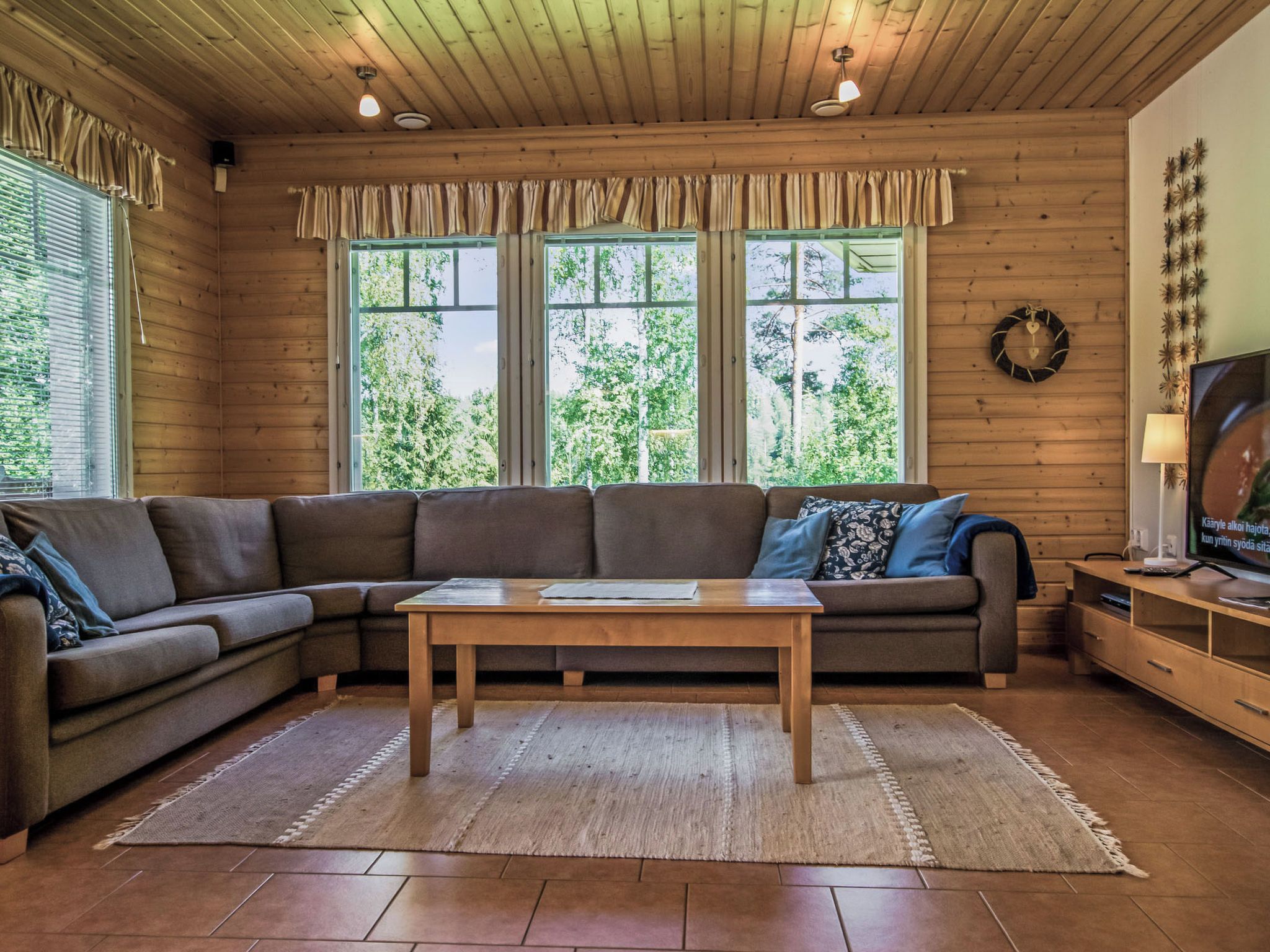 A cozy living room with a sectional sofa, a wooden coffee table, and a television on a wooden stand.