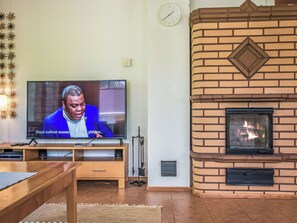 Una sala de estar con televisión, chimenea y un reloj en la pared.