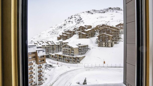 Ett snötäckt berg med en rad byggnader i chaletstil.