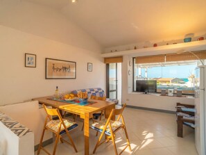 Un comedor con una mesa, sillas y vista al mar.