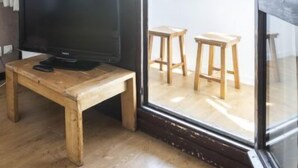 Quarto com uma mesa de madeira, televisão e uma grande janela com vista para uma paisagem nevada.
