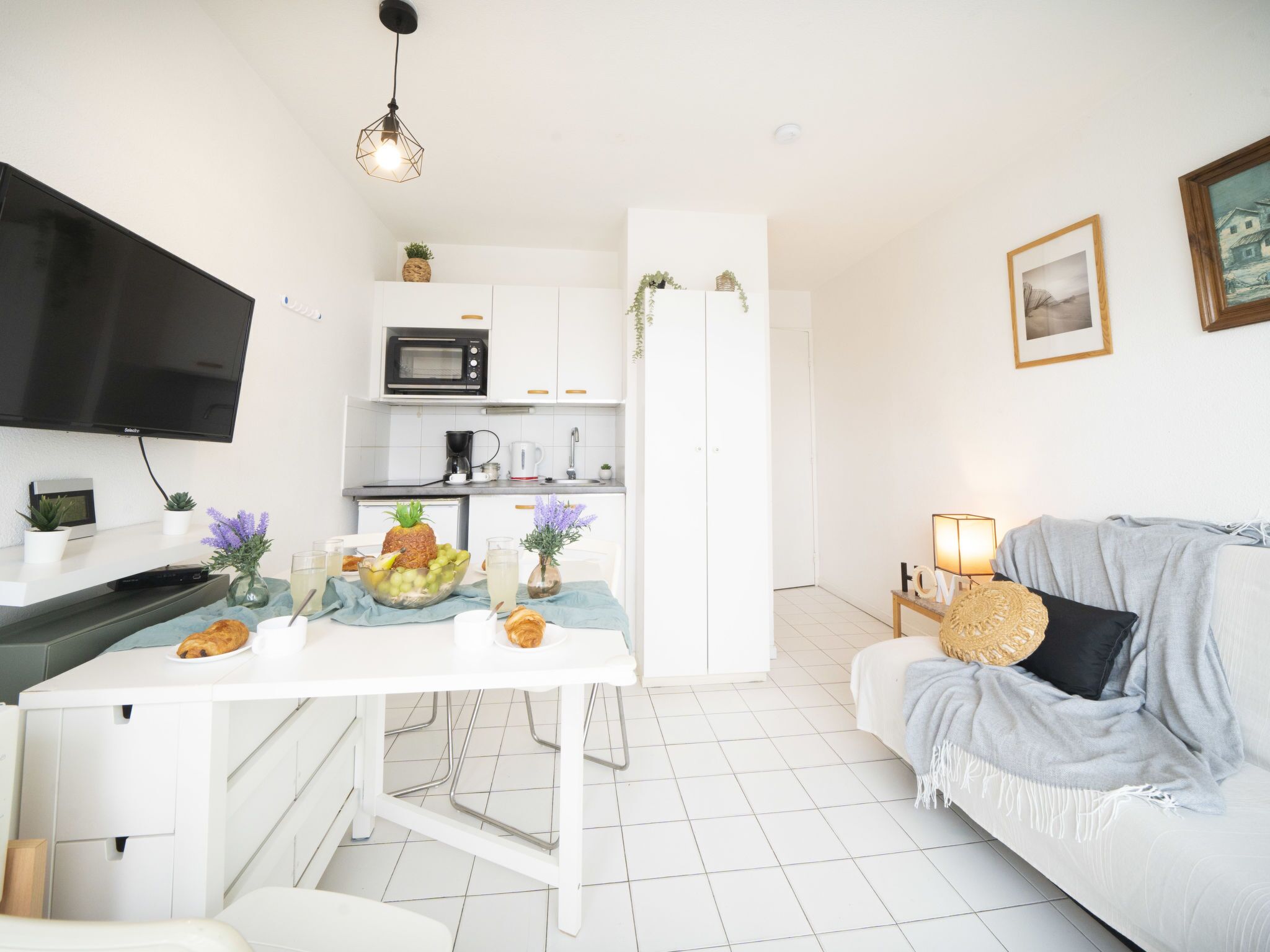 A modern kitchen with white cabinetry, a microwave, and a dining area with a table set for two.