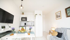 Une cuisine moderne avec des meubles blancs, un four à micro-ondes et un coin repas avec une table dressée pour deux personnes.