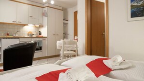 A hotel room with two beds, a kitchen area, and a door leading to another room. - Chalet Abendrot apARTments by Interhome (Grindelwald)