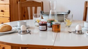 Une table de petit-déjeuner avec du pain, des œufs, des condiments et une carafe.