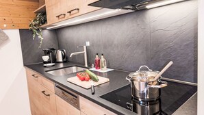 Une cuisine moderne avec un plan de travail noir, des appareils en acier inoxydable et des armoires en bois.