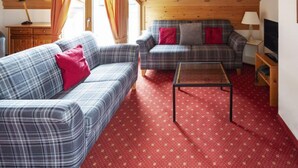 A cozy living room with two plaid sofas, a coffee table, and a red patterned carpet. - Chalet Abendrot apARTments by Interhome (Grindelwald)