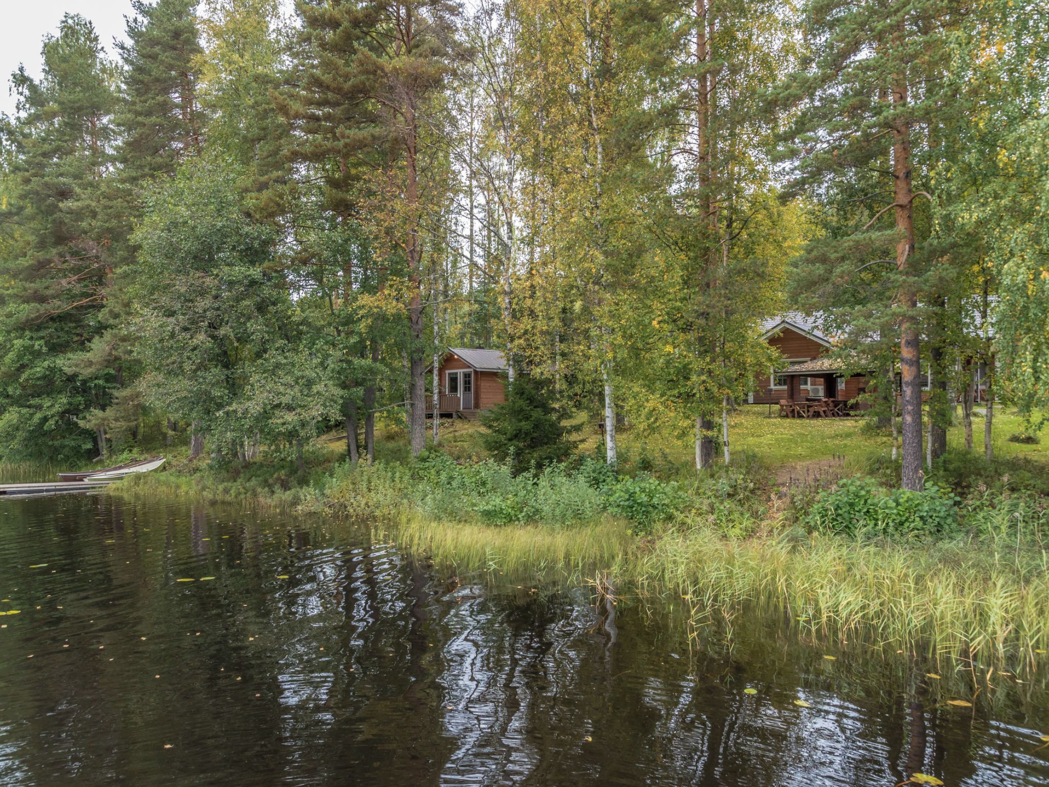 A cabin surrounded by forest, a dock, and a calm lake.