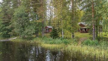 A cabin surrounded by forest, a dock, and a calm lake.