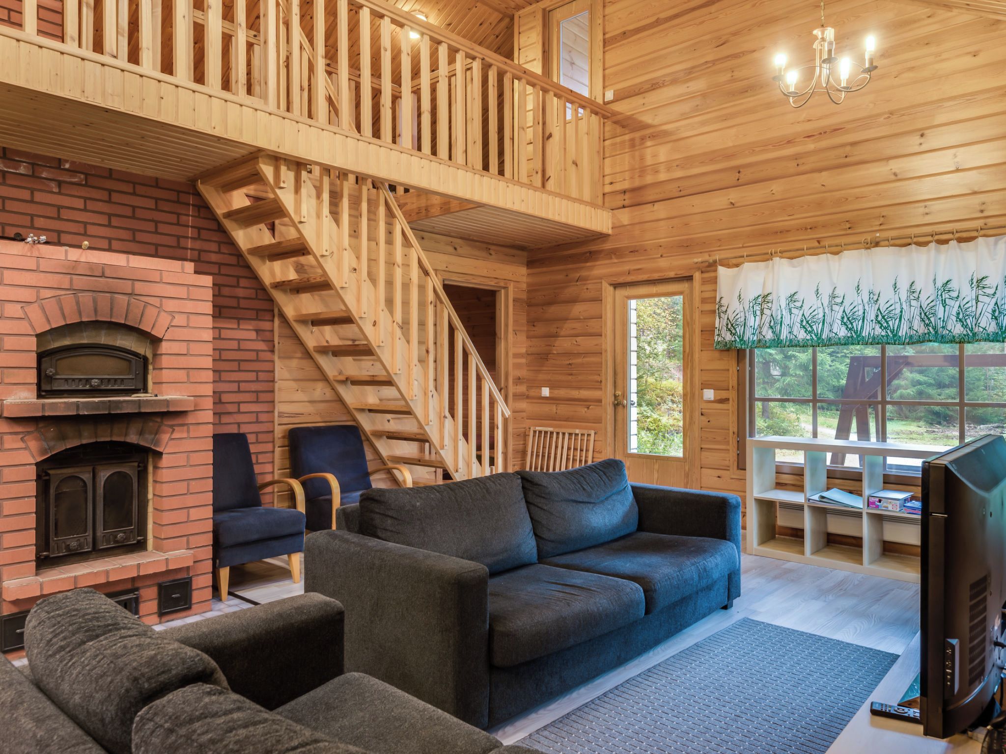 Ein Holzinnenraum mit Kamin, einer Couch, einem Fernseher und einer Treppe.