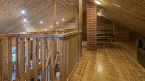 Un intérieur en bois avec un plafond haut, une colonne en briques et un escalier en bois.