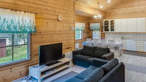 Un chalet confortable avec un intérieur en bois, une télévision, un canapé et un coin repas.