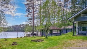 Une propriété au bord du lac, dotée d’une terrasse couverte, d’un petit chalet et d’une maison avec un porche.