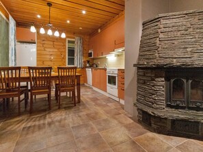 Une cuisine avec des meubles en bois, une cheminée en pierre et une table à manger avec des chaises.