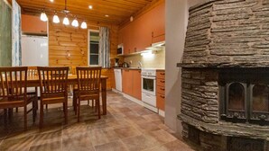 Una cocina con armarios de madera, una chimenea de piedra y un comedor con mesa y sillas de madera.