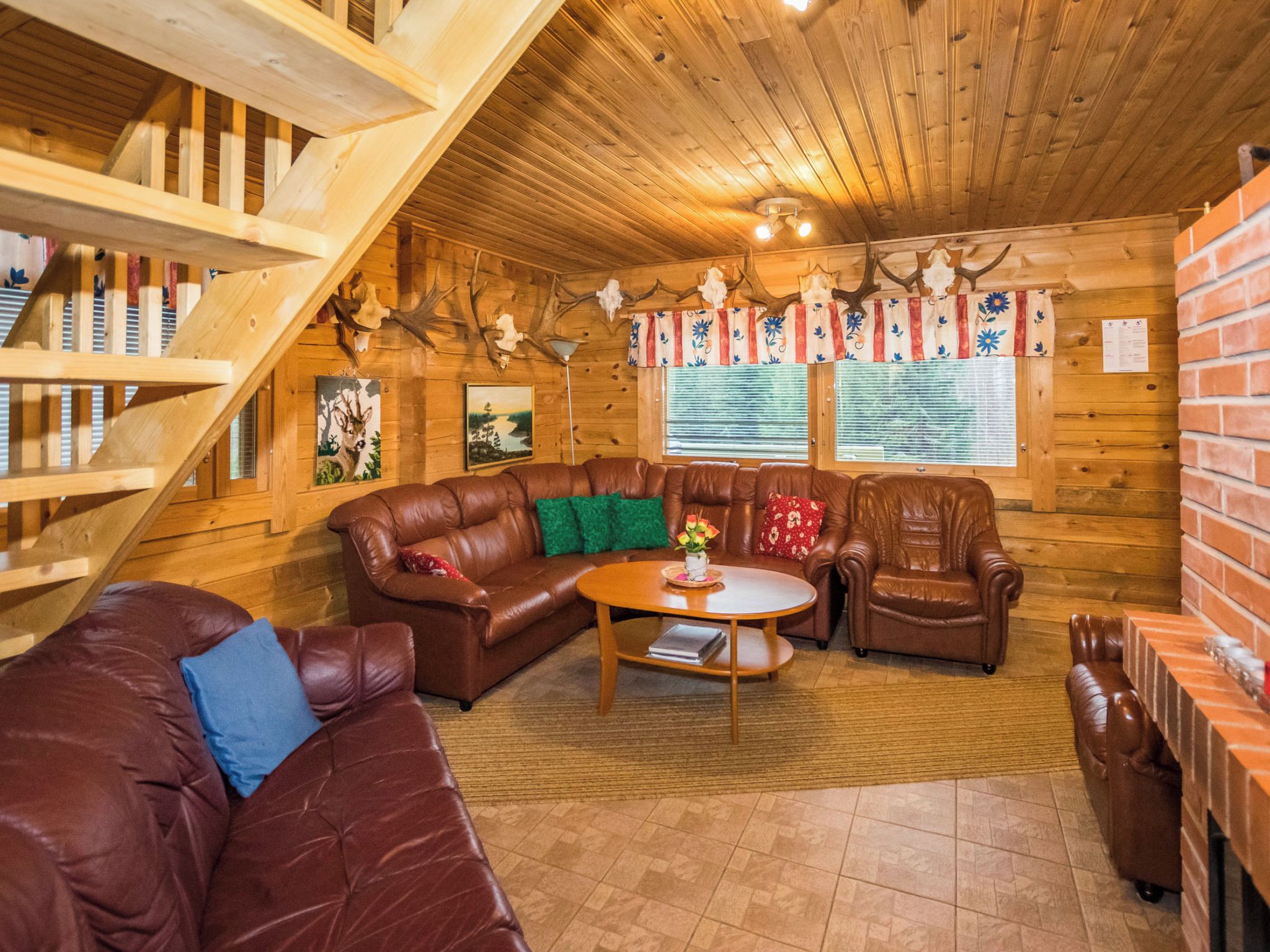 Ein Holzblockhaus-Interieur mit einer Holztreppe, Ledermöbeln und Geweih-Dekorationen.