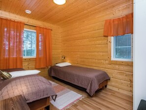 A wooden cabin room with two beds, a small table, and a window with blinds. - Vacation home Kuutti by Interhome (Punkaharju)