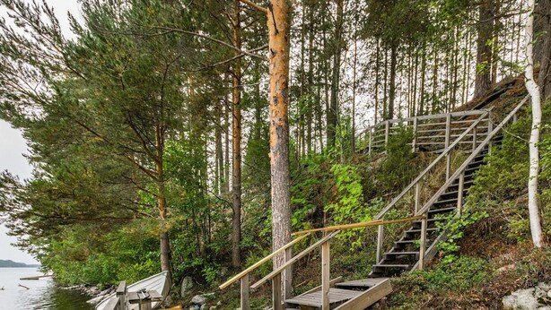 A wooden deck with a staircase leading up to a platform, surrounded by dense forest and overlooking a body of water. - Vacation home Kuutti by Interhome (Punkaharju)