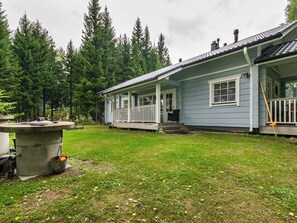 A house with a porch, surrounded by a grassy yard and tall trees. - Vacation home Kuutti by Interhome (Punkaharju)