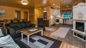A cozy log cabin interior with a living room, dining area, kitchen, and fireplace. - Vacation home Kuutti by Interhome (Punkaharju)