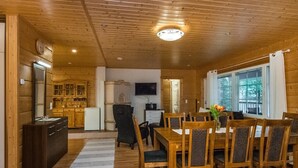 A wooden interior with a dining area, kitchen, and a large window. - Vacation home Kuutti by Interhome (Punkaharju)