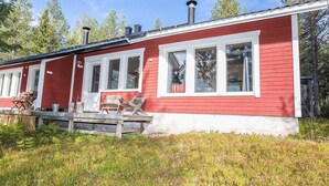 A red cabin with white trim, large windows, and a deck with outdoor furniture. - Rintelä 5a by Interhome (Kuusamo)