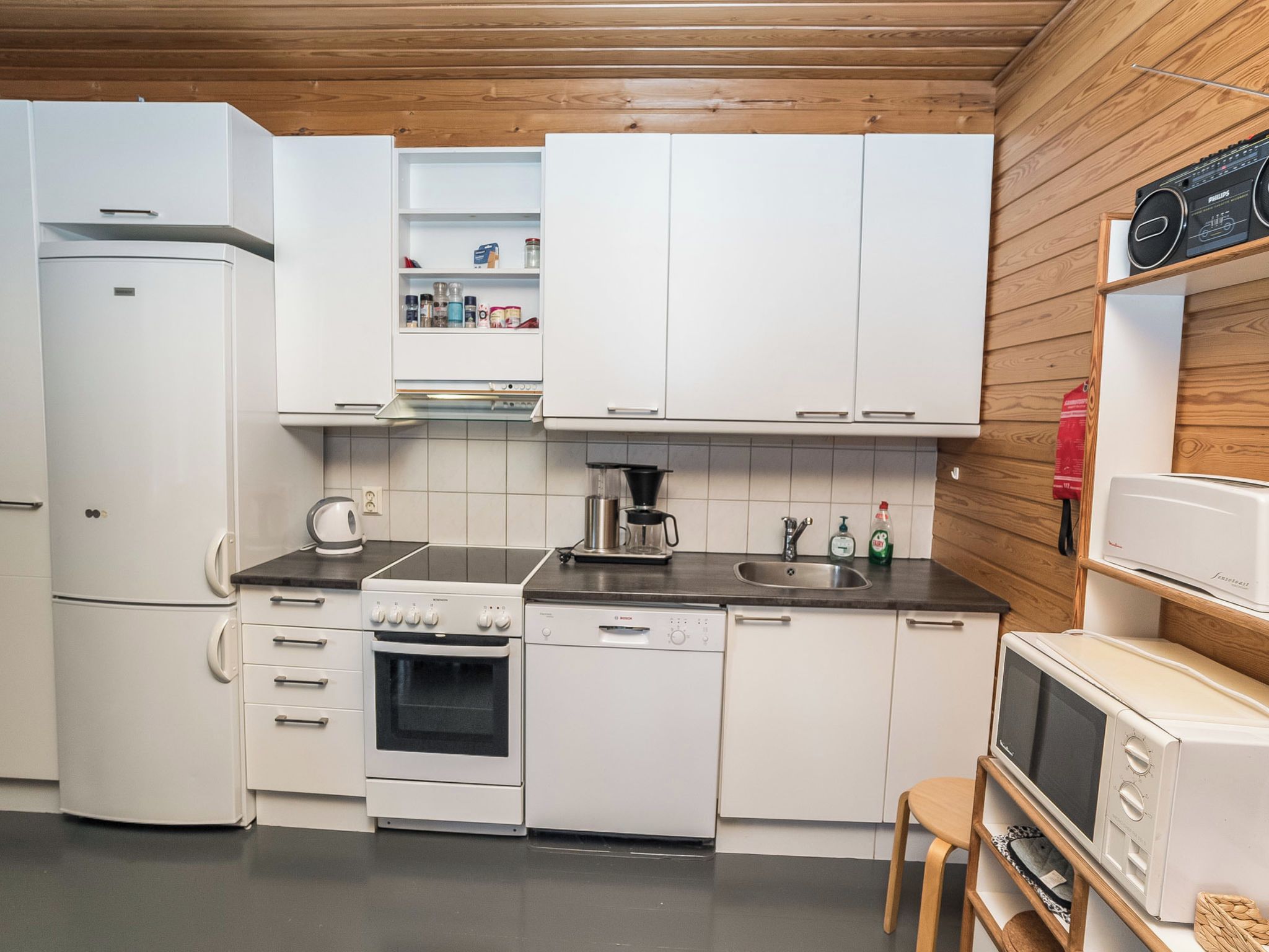 A compact kitchen with white cabinetry, a stove, oven, dishwasher, and a microwave.
