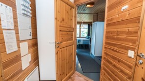 A wooden interior with a white door, a radiator, and a dining area visible through the door. - Rintelä 5a by Interhome (Kuusamo)